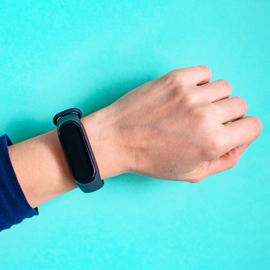 fitbit watch on wrist on blue background